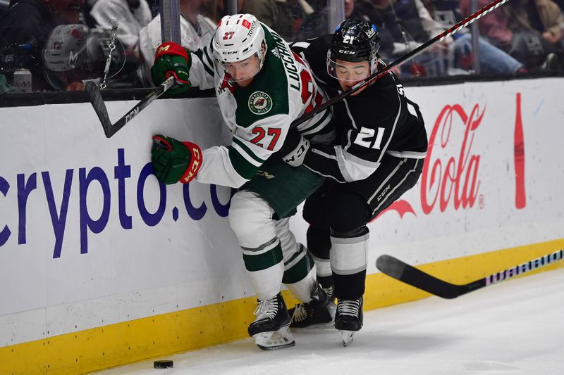 Mar 20, 2024; Los Angeles, California, USA; Los Angeles Kings defenseman Jordan Spence (21) plays for the puck against Minnesota Wild center Jacob Lucchini (27) during the third period at Crypto.com Arena. Mandatory Credit: Gary A. Vasquez-USA TODAY Sports