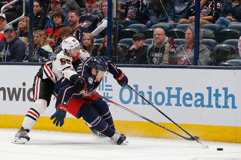 Nov 22, 2023; Columbus, Ohio, USA; Chicago Blackhawks defenseman Kevin Korchinski (55) sticks the puck away from Columbus Blue Jackets right wing Mathieu Olivier (24) during the third period at Nationwide Arena. Mandatory Credit: Russell LaBounty-USA TODAY Sports