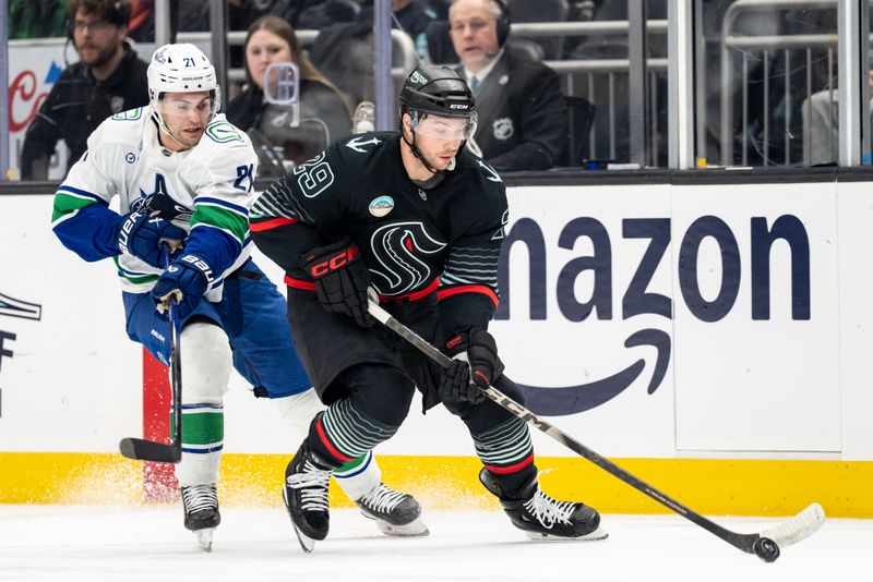Dec 29, 2025; Seattle, Washington, USA; Seattle Kraken forward Jared McCann (19) skates against Vancouver Canucks forward Nils Hoglander (21) during the second period  at Climate Pledge Arena. Mandatory Credit: Stephen Brashear-Imagn Images