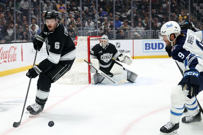 Apr 1, 2025; Los Angeles, California, USA;  Los Angeles Kings defenseman Joel Edmundson (6) controls the puck against Winnipeg Jets left wing Alex Iafallo (9) during the first period at Crypto.com Arena. Mandatory Credit: Kiyoshi Mio-Imagn Images