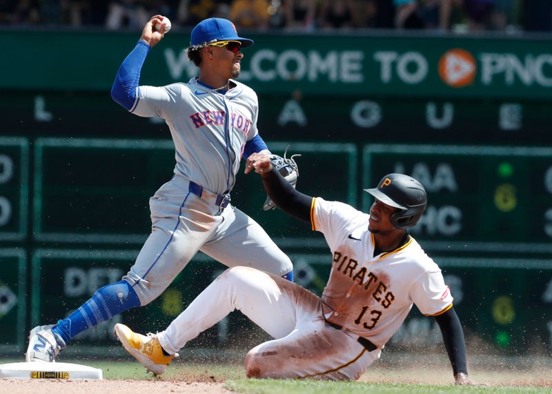 Jul 7, 2024; Pittsburgh, Pennsylvania, USA;  New York Mets shortstop Francisco Lindor (12) turns a double play over Pittsburgh Pirates third baseman Ke'Bryan Hayes (13) during the seventh inning at PNC Park. The Mets won 3-2. Mandatory Credit: Charles LeClaire-USA TODAY Sports