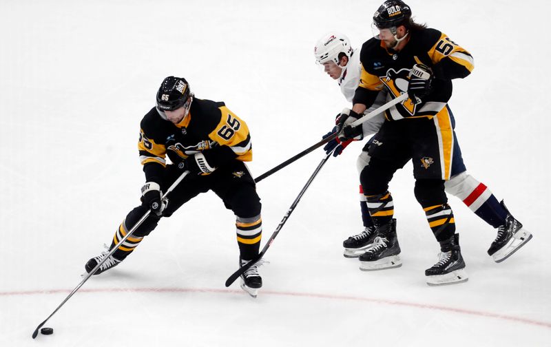 Jan 2, 2024; Pittsburgh, Pennsylvania, USA;  Pittsburgh Penguins defenseman Erik Karlsson (65) handles the puck as Pittsburgh Penguins defenseman Kris Letang (58) sets a pick on Washington Capitals center Connor McMichael (24) during the third period at PPG Paints Arena. Mandatory Credit: Charles LeClaire-USA TODAY Sports