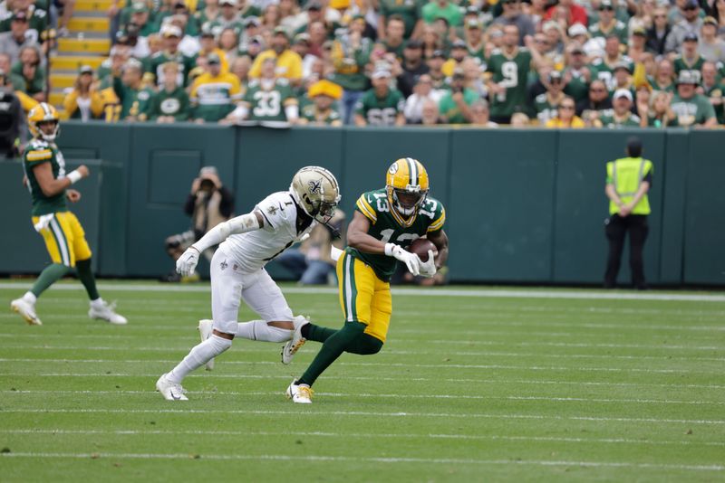 Green Bay Packers wide receiver Dontayvion Wicks (13) gets tackles by New Orleans Saints cornerback Alontae Taylor (1) during an NFL football game Sunday, Sept. 24, 2023, in Green Bay, Wis. (AP Photo/Mike Roemer)