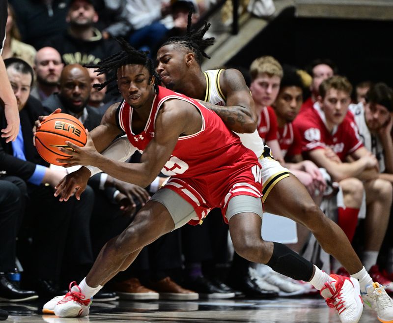 Mar 10, 2024; West Lafayette, Indiana, USA;  Wisconsin Badgers guard John Blackwell (25) reaches to keep a ball in bounds in front of Purdue Boilermakers guard Lance Jones (55) during the second half at Mackey Arena. Mandatory Credit: Marc Lebryk-USA TODAY Sports