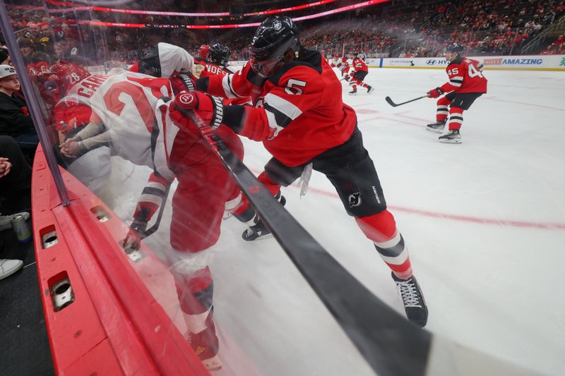 Jan 4, 2026; Newark, New Jersey, USA; New Jersey Devils defenseman Brenden Dillon (5) hits Carolina Hurricanes left wing William Carrier (28) during the first period at Prudential Center. Mandatory Credit: Ed Mulholland-Imagn Images
