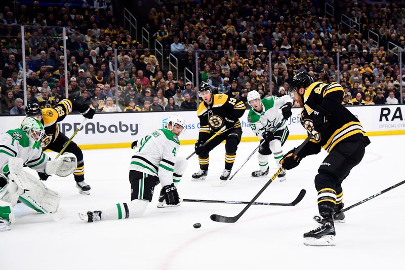 Oct 24, 2024; Boston, Massachusetts, USA;  Boston Bruins right wing David Pastrnak (88) pass the puck while Dallas Stars defenseman Miro Heiskanen (4) defends in front of goaltender Casey DeSmith (1) during the first period at TD Garden. Mandatory Credit: Bob DeChiara-Imagn Images