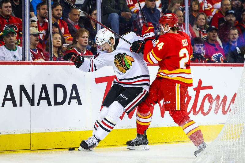 Oct 15, 2024; Calgary, Alberta, CAN; Chicago Blackhawks right wing Joey Anderson (22) and Calgary Flames defenseman Jake Bean (24) battles for the puck during the first period at Scotiabank Saddledome. Mandatory Credit: Sergei Belski-Imagn Images