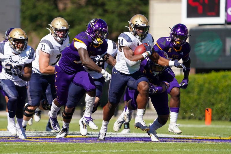 Oct 17, 2020; Greenville, North Carolina, USA;  Navy Midshipmen fullback Jamale Carothers (34) runs with the ball past defensive back East Carolina Pirates Jireh Wilson (35) and defensive back Shawn Dourseau (27) during the first half at Dowdy-Ficklen Stadium. Mandatory Credit: James Guillory-USA TODAY Sports