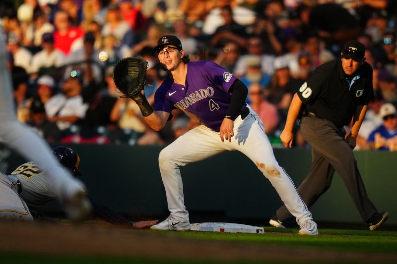 Jul 2, 2024; Denver, Colorado, USA; Colorado Rockies first base Michael Toglia (4) fields the ball as Milwaukee Brewers outfielder Christian Yelich (22) slides back to first base in the fifth inning at Coors Field. Mandatory Credit: Ron Chenoy-USA TODAY Sports