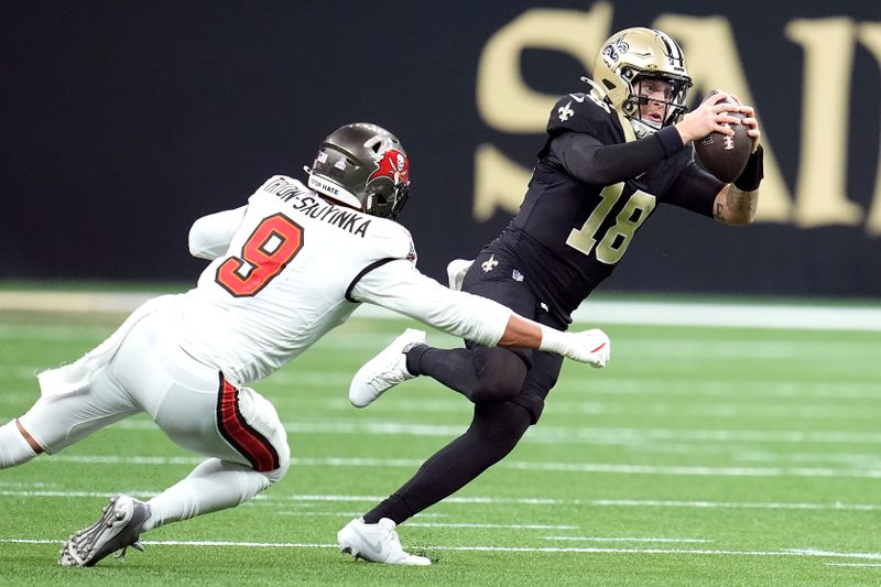 New Orleans Saints quarterback Spencer Rattler (18) runs against Tampa Bay Buccaneers linebacker Joe Tryon-Shoyinka (9) during the first half of an NFL football game in New Orleans, Sunday, Oct. 13, 2024. (AP Photo/Michael Conroy)