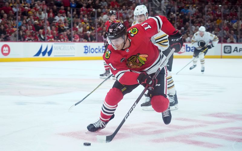 Oct 24, 2023; Chicago, Illinois, USA; Boston Bruins defenseman Ian Mitchell (14) defends Chicago Blackhawks right wing Taylor Raddysh (11) during the first period against the Boston Bruins at United Center. Mandatory Credit: David Banks-USA TODAY Sports