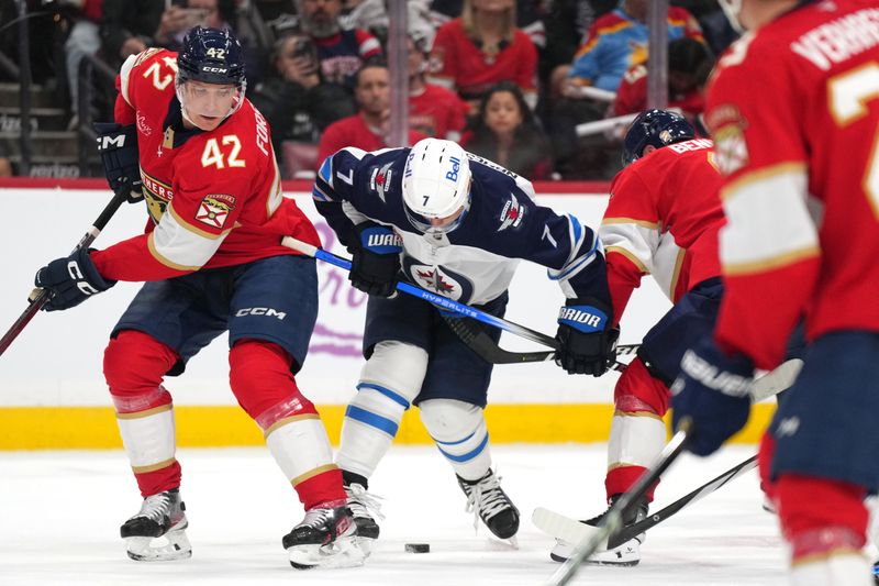 Nov 16, 2024; Sunrise, Florida, USA;  Winnipeg Jets center Vladislav Namestnikov (7) and Florida Panthers defenseman Gustav Forsling (42) battle for possession during the first period at Amerant Bank Arena. Mandatory Credit: Jim Rassol-Imagn Images