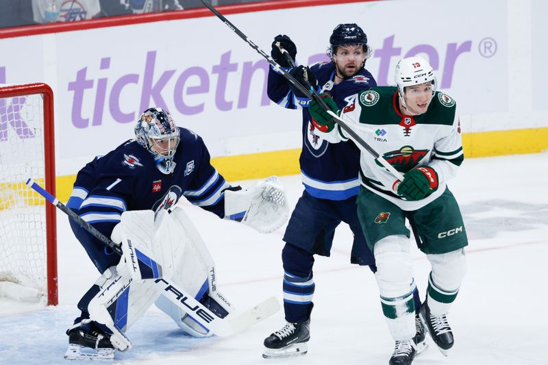 Nov 23, 2025; Winnipeg, Manitoba, CAN;  Winnipeg Jets defenseman Josh Morrissey (44) jostles for position with Minnesota Wild forward Yakov Trenin (13) in front of Winnipeg Jets goalie Eric Comrie (1) during the second period at Canada Life Centre. Mandatory Credit: Terrence Lee-Imagn Images