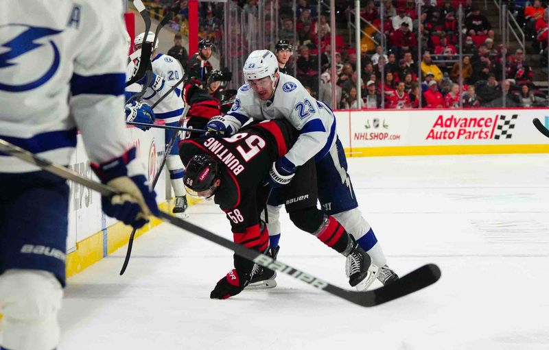 Nov 24, 2023; Raleigh, North Carolina, USA; Tampa Bay Lightning center Michael Eyssimont (23) battles Carolina Hurricanes left wing Michael Bunting (58) during the third period at PNC Arena. Mandatory Credit: James Guillory-USA TODAY Sports