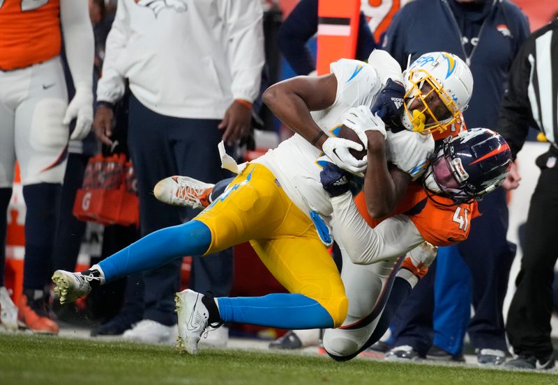 Los Angeles Chargers running back Isaiah Spiller (28) is pulled down byh Denver Broncos linebacker Drew Sanders (41) in the second half of an NFL football game in Empower Field at Mile High Sunday, Dec. 31, 2023, in Denver. (AP Photo/David Zalubowski)