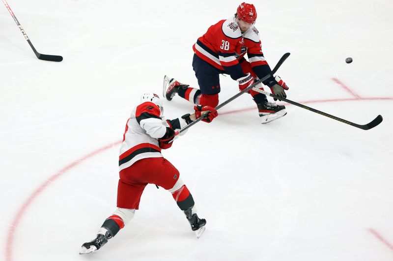 Jan 31, 2026; Washington, District of Columbia, USA; Carolina Hurricanes defenseman Shayne Gostisbehere (4) takes a shot past Washington Capitals defenseman Rasmus Sandin (38) during the third period at Capital One Arena. Mandatory Credit: Daniel Kucin Jr.-Imagn Images