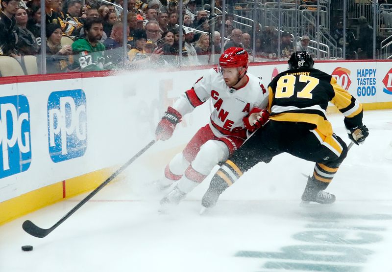 Oct 18, 2024; Pittsburgh, Pennsylvania, USA;  Carolina Hurricanes defenseman Jaccob Slavin (74) reaches for the puck against Pittsburgh Penguins center Sidney Crosby (87) during the first period at PPG Paints Arena. Mandatory Credit: Charles LeClaire-Imagn Images