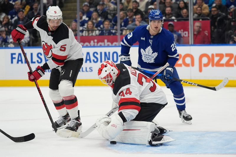 Oct 21, 2025; Toronto, Ontario, CAN; New Jersey Devils goaltender Jake Allen (34) covers up a rebound in front of defenseman Brenden Dillon (5) and Toronto Maple Leafs forward Matthew Knies (23) during the third period at Scotiabank Arena. Mandatory Credit: John E. Sokolowski-Imagn Images