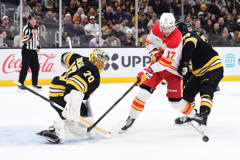 Jan 8, 2026; Boston, Massachusetts, USA; Boston Bruins defenseman Charlie McAvoy (73) and Calgary Flames center Yegor Sharangovich (17) battle for the puck in front of goaltender Joonas Korpisalo (70) during the second period at TD Garden. Mandatory Credit: Bob DeChiara-Imagn Images