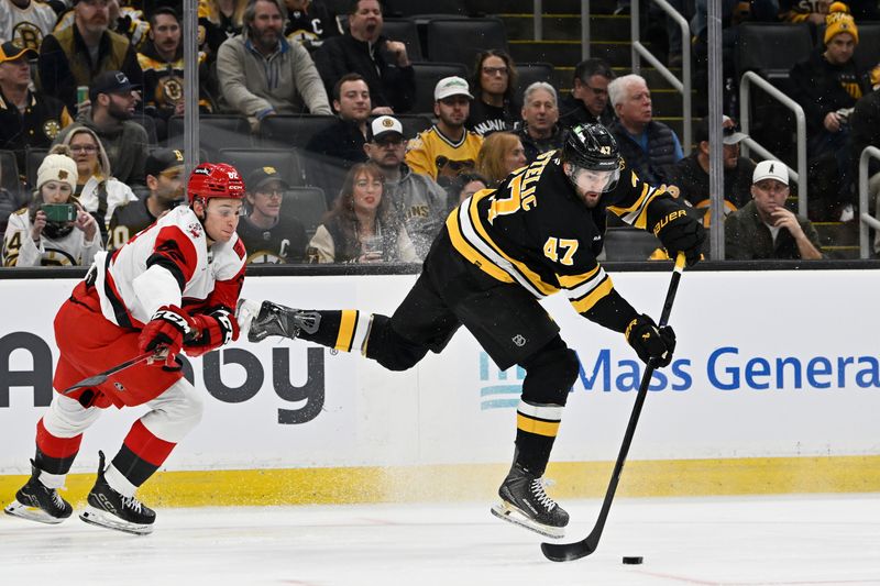 Nov 1, 2025; Boston, Massachusetts, USA; Boston Bruins center Mark Kastelic (47) plays the puck with pressure from Carolina Hurricanes center Jesperi Kotkaniemi (82) during the first period at TD Garden. Mandatory Credit: Eric Canha-Imagn Images