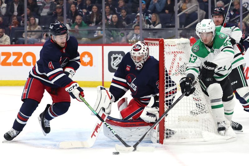 Nov 9, 2024; Winnipeg, Manitoba, CAN; Dallas Stars center Wyatt Johnston (53) has his wrap around shot stopped by Winnipeg Jets defenseman Neal Pionk (4) in front of Winnipeg Jets goaltender Connor Hellebuyck (37) in the first period at Canada Life Centre. Mandatory Credit: James Carey Lauder-Imagn Images