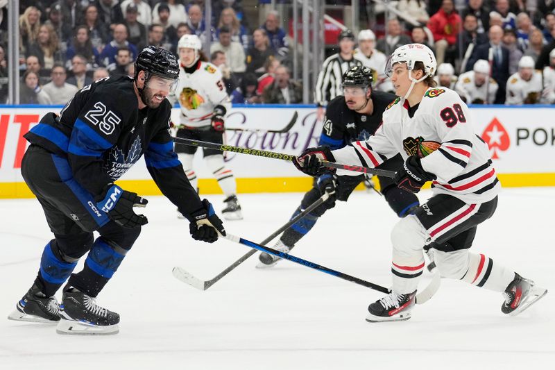 Dec 2, 2024; Toronto, Ontario, CAN; Toronto Maple Leafs defenseman Conor Timmins (25) blocks a shot from Chicago Blackhawks forward Connor Bedard (98) as Toronto Maple Leafs forward Auston Matthews (34) closes in during the second period at Scotiabank Arena. Mandatory Credit: John E. Sokolowski-Imagn Images