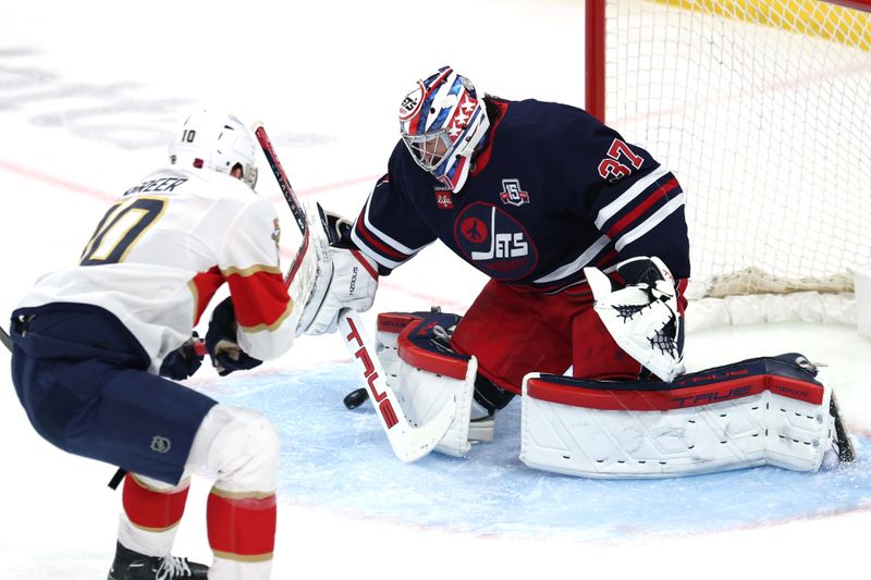 Jan 22, 2026; Winnipeg, Manitoba, CAN; Winnipeg Jets goaltender Connor Hellebuyck (37) blocks a shot from Florida Panthers left wing A.J. Greer (10) in the first period at Canada Life Centre. Mandatory Credit: James Carey Lauder-Imagn Images