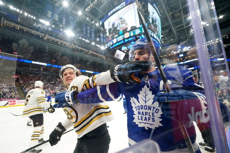 Apr 24, 2024; Toronto, Ontario, CAN; Boston Bruins forward David Pastrnak (88) and Toronto Maple Leafs forward John Tavares (91) battle along the boards during the first period of game three of the first round of the 2024 Stanley Cup Playoffs at Scotiabank Arena. Mandatory Credit: John E. Sokolowski-USA TODAY Sports