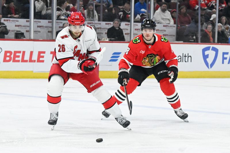 Jan 20, 2025; Chicago, Illinois, USA;  Carolina Hurricanes defenseman Sean Walker (26) moves the puck against Chicago Blackhawks center Ryan Donato (8) during the first period at the United Center. Mandatory Credit: Matt Marton-Imagn Images
