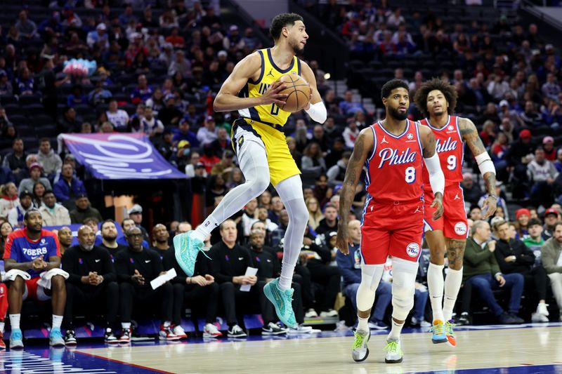 PHILADELPHIA, PENNSYLVANIA - DECEMBER 13: Tyrese Haliburton #0 of the Indiana Pacers passes the ball against Paul George #8 and Kelly Oubre Jr. #9 of the Philadelphia 76ers during the first half at the Wells Fargo Center on December 13, 2024 in Philadelphia, Pennsylvania. NOTE TO USER: User expressly acknowledges and agrees that, by downloading and or using this photograph, User is consenting to the terms and conditions of the Getty Images License Agreement. (Photo by Emilee Chinn/Getty Images)