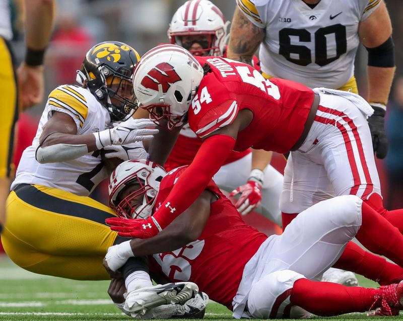 Oct 14, 2023; Madison, Wisconsin, USA; Wisconsin Badgers linebackers Maema Njongmeta (55) and Jordan Turner (54) tackle Iowa Hawkeyes running back Kaleb Johnson (2) at Camp Randall Stadium. Mandatory Credit: Tork Mason-USA TODAY Sports