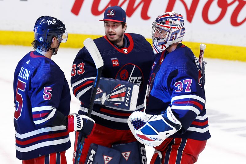 Apr 2, 2023; Winnipeg, Manitoba, CAN; Winnipeg Jets defenseman Brenden Dillon (5), Winnipeg Jets goaltender David Rittich (33) and Winnipeg Jets goaltender Connor Hellebuyck (37) celebrate their victory over the New Jersey Devils at Canada Life Centre. Mandatory Credit: James Carey Lauder-USA TODAY Sports