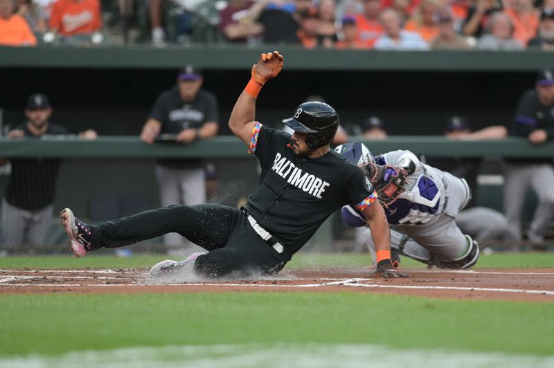 Aug 25, 2023; Baltimore, Maryland, USA;  Baltimore Orioles right fielder Anthony Santander (25) slides past Colorado Rockies catcher Elias Diaz (35) to score during the first inning at Oriole Park at Camden Yards. Mandatory Credit: Tommy Gilligan-USA TODAY Sports