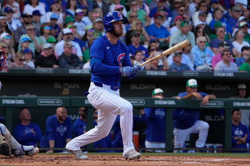 Mar 17, 2024; Mesa, Arizona, USA; Chicago Cubs centerfielder Cody Bellinger (24) hits an RBI sacrifice fly-out in the first inning during a game against the Texas Rangers at Sloan Park. Mandatory Credit: Rick Scuteri-USA TODAY Sports