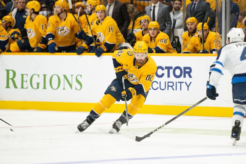 Nov 23, 2024; Nashville, Tennessee, USA;  Nashville Predators center Tommy Novak (82) skates with the puck against against the Winnipeg Jets during the first period at Bridgestone Arena. Mandatory Credit: Steve Roberts-Imagn Images