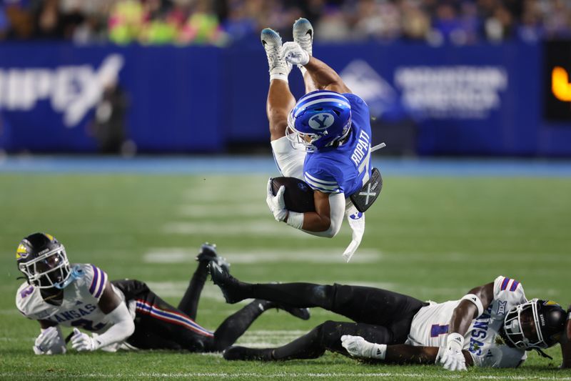 Nov 16, 2024; Provo, Utah, USA; Brigham Young Cougars running back Hinckley Ropati (7) is tackled by Kansas Jayhawks linebacker JB Brown (1) and cornerback Cobee Bryant (2) during the first quarter at LaVell Edwards Stadium. Mandatory Credit: Rob Gray-Imagn Images