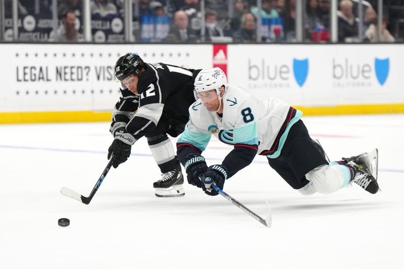 Dec 20, 2023; Los Angeles, California, USA; Seattle Kraken defenseman Brian Dumoulin (8) and LA Kings left wing Trevor Moore (12) reach for the puck in the second period at Crypto.com Arena. Mandatory Credit: Kirby Lee-USA TODAY Sports