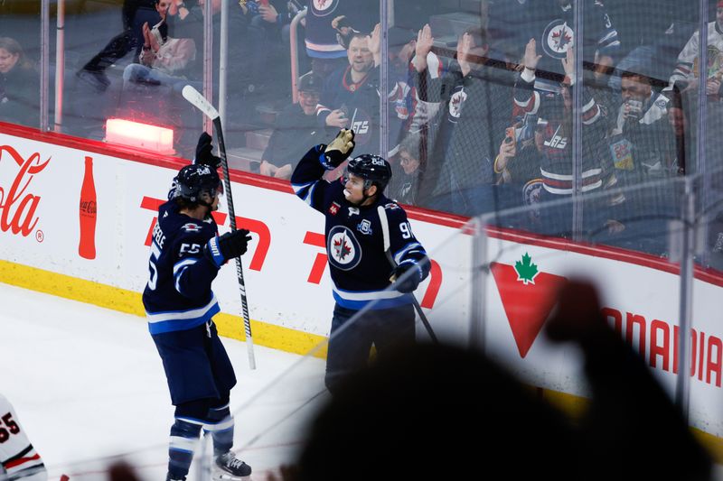 Mar 3, 2026; Winnipeg, Manitoba, CAN;  Winnipeg Jets forward Mark Scheifele (55) is congratulated by forward Cole Perfetti (91) after a game-winning goal against the Chicago Blackhawks during overtime at Canada Life Centre. Mandatory Credit: Terrence Lee-Imagn Images