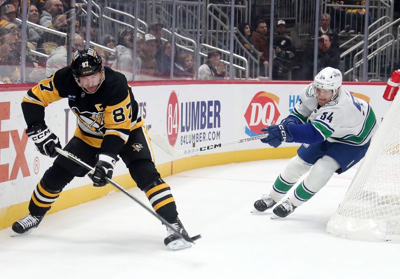Nov 27, 2024; Pittsburgh, Pennsylvania, USA;  Pittsburgh Penguins center Sidney Crosby (87) clears the puck from behind his net against pressure from Vancouver Canucks center Aatu Raty (54) during the second period at PPG Paints Arena. Mandatory Credit: Charles LeClaire-Imagn Images