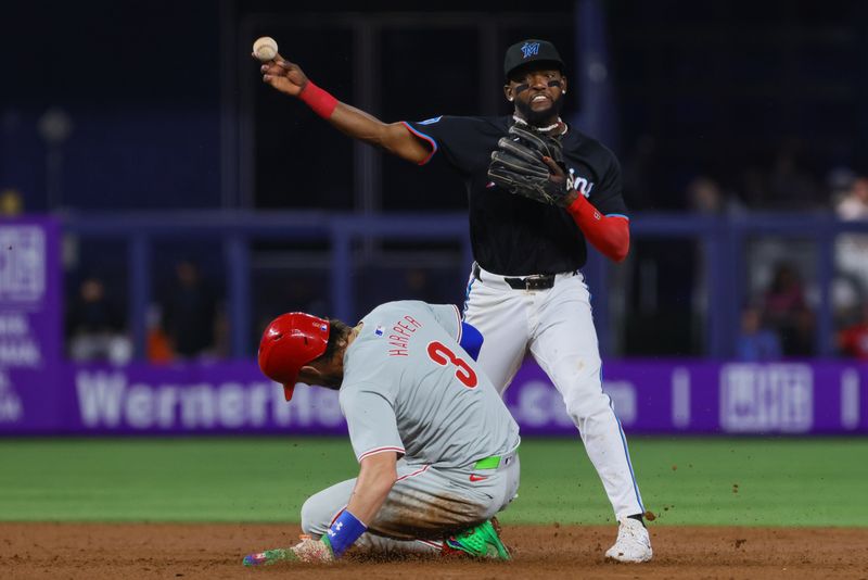 May 10, 2024; Miami, Florida, USA; Miami Marlins second baseman Vidal Brujan (17) turns a double play as Philadelphia Phillies first baseman Bryce Harper (3) slides at second base during the third inning at loanDepot Park. Mandatory Credit: Sam Navarro-USA TODAY Sports