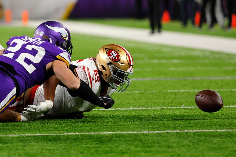 Minnesota Vikings safety Harrison Smith (22) and San Francisco 49ers guard Aaron Banks (65) fight to recover a fumble during the first half of an NFL football game, Monday, Oct. 23, 2023, in Minneapolis. (AP Photo/Bruce Kluckhohn)