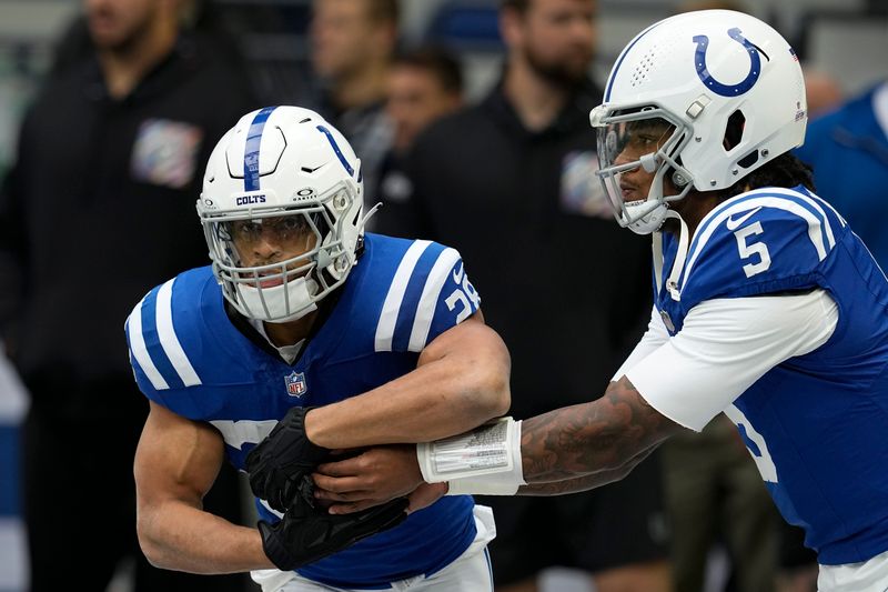 Indianapolis Colts running back Jonathan Taylor, left, takes the ball from quarterback Anthony Richardson (5) as they warm up before an NFL football game against the Tennessee Titans, Sunday, Oct. 8, 2023, in Indianapolis. (AP Photo/Darron Cummings)