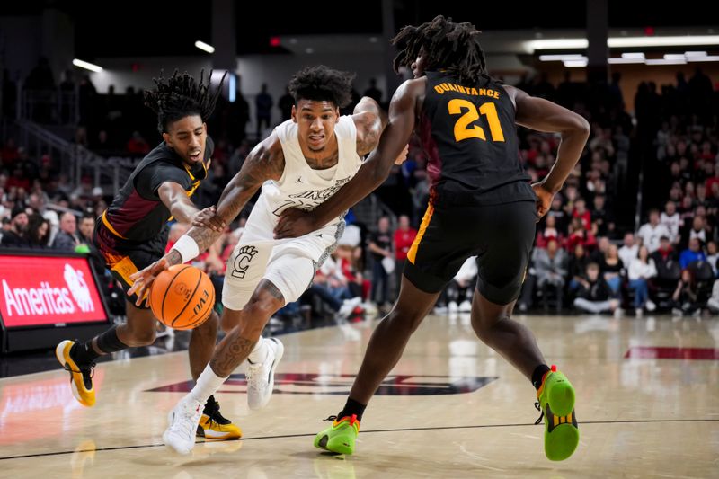 Jan 18, 2025; Cincinnati, Ohio, USA;  Cincinnati Bearcats forward Dillon Mitchell (23) dribbles the ball against Arizona State Sun Devils guard Amier Ali (5) and forward Jayden Quaintance (21) in the first half at Fifth Third Arena. Mandatory Credit: Aaron Doster-Imagn Images