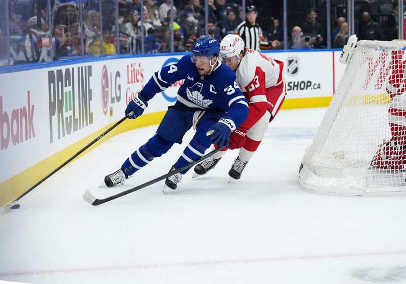 Oct 2, 2025; Toronto, Ontario, CAN; Toronto Maple Leafs center Auston Matthews (34) battles for the puck with Detroit Red Wings defenseman Moritz Seider (53) during the first period at Scotiabank Arena. Mandatory Credit: Nick Turchiaro-Imagn Images