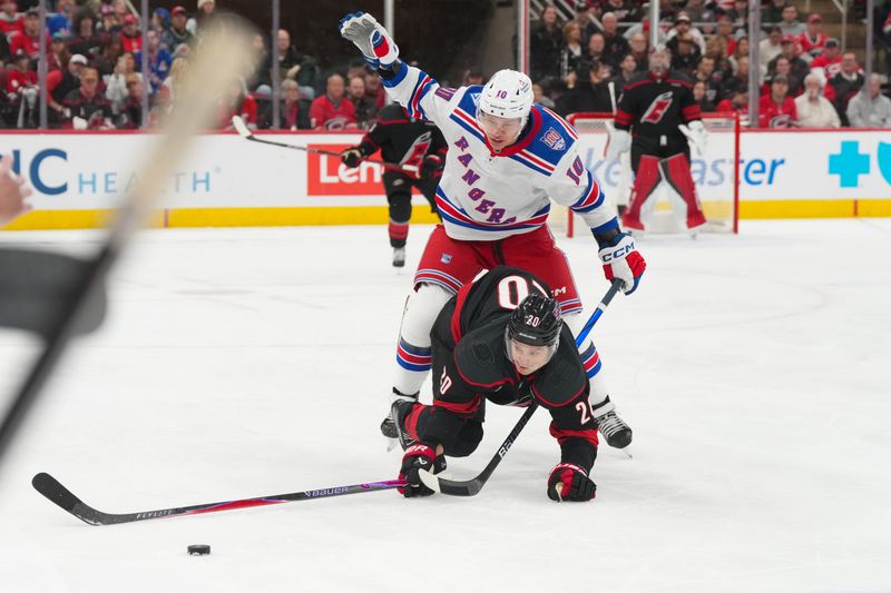 Nov 15, 2025; Raleigh, North Carolina, USA; Carolina Hurricanes center Sebastian Aho (20) is tripped by New York Rangers left wing Artemi Panarin (10) during the first period at Lenovo Center. Mandatory Credit: James Guillory-Imagn Images