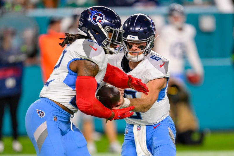 Tennessee Titans quarterback Will Levis (8) hands off the ball to running back Derrick Henry (22) during an NFL football game against the Miami Dolphins, Monday, Dec. 12, 2023, in Miami Gardens, Fla. (AP Photo/Doug Murray)