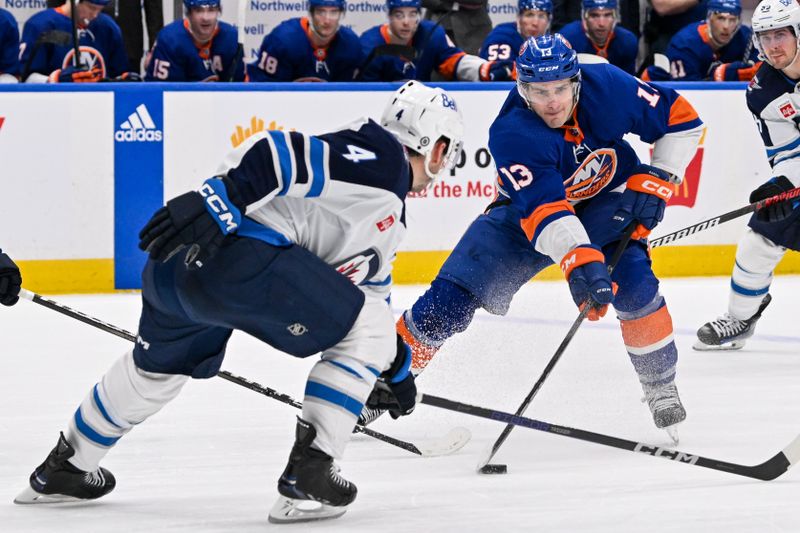 Mar 23, 2024; Elmont, New York, USA;  New York Islanders center Mathew Barzal (13) attempts a pass defended by Winnipeg Jets defenseman Neal Pionk (4) during the second period at UBS Arena. Mandatory Credit: Dennis Schneidler-USA TODAY Sports