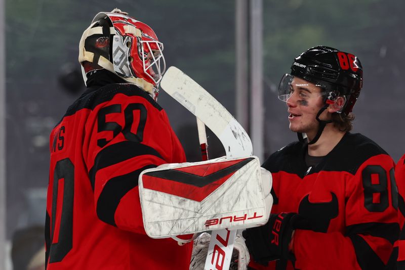 Feb 17, 2024; East Rutherford, New Jersey, USA; New Jersey Devils goaltender Nico Daws (50) and center Jack Hughes (86) celebrate their win over the Philadelphia Flyers in a Stadium Series ice hockey game at MetLife Stadium. Mandatory Credit: Ed Mulholland-USA TODAY Sports