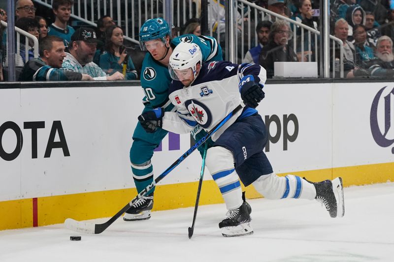 Nov 7, 2025; San Jose, California, USA;  Winnipeg Jets defenseman Neal Pionk (4) vies for the puck against San Jose Sharks center Ty Dellandrea (10) during the second period at SAP Center at San Jose. Mandatory Credit: David Gonzales-Imagn Images