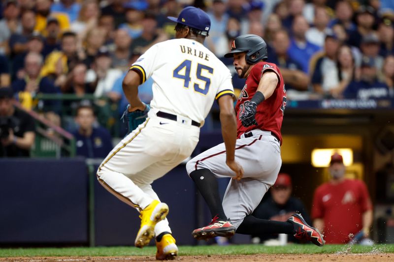 Oct 4, 2023; Milwaukee, Wisconsin, USA; Arizona Diamondbacks left fielder Tommy Pham (28) scores against Milwaukee Brewers relief pitcher Abner Uribe (45) on a wild pitch in the sixth inning during game two of the Wildcard series for the 2023 MLB playoffs at American Family Field. Mandatory Credit: Kamil Krzaczynski-USA TODAY Sports